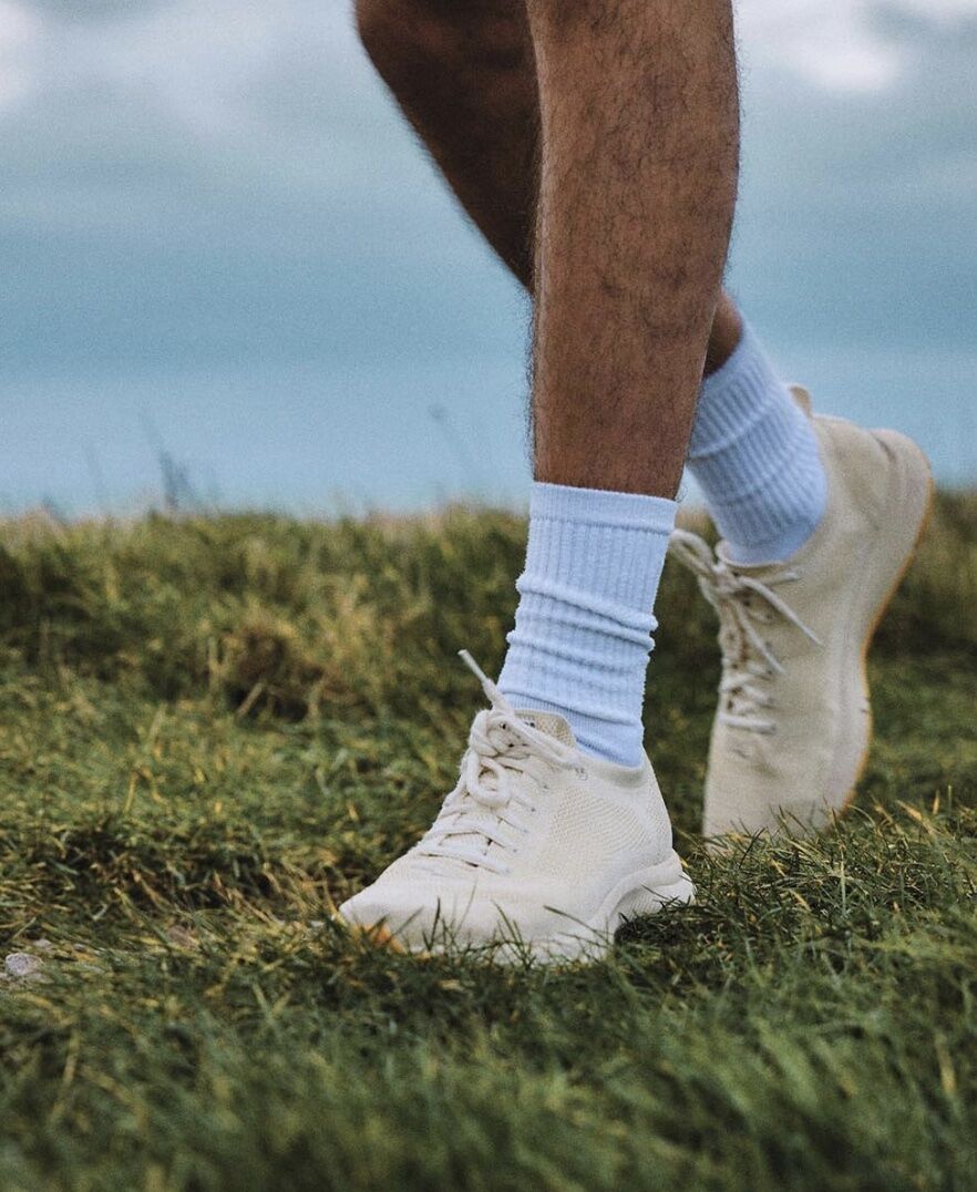 man wearing walking shoes on grassy cliff