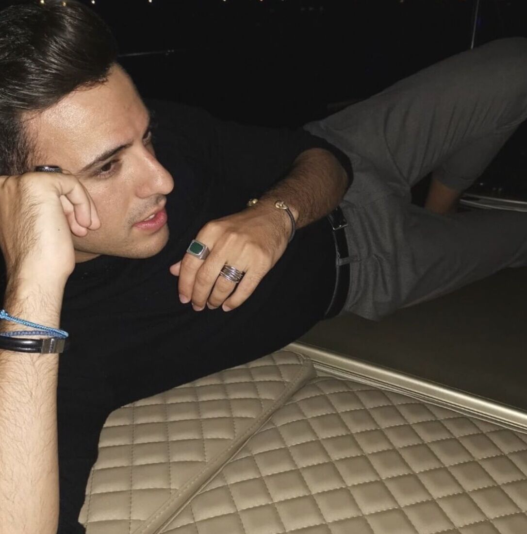 Man laying on side dressed in a black shirt and slacks wearing the best rings for men on hands