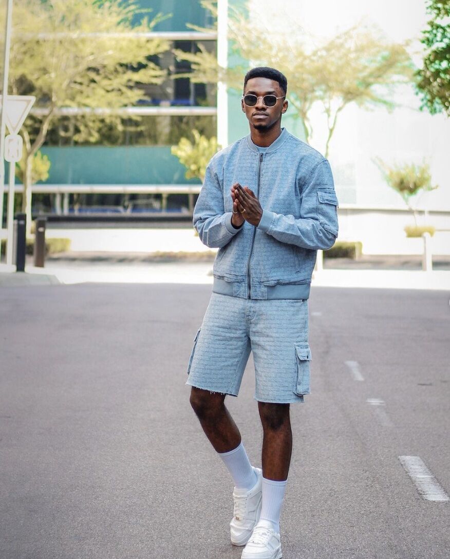 Man wearing matching blue bomber jacket and cargo short set with white sneakers