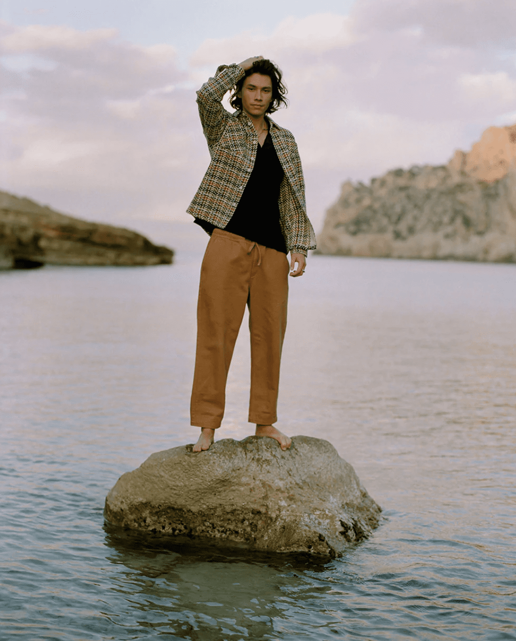 Man standing on a rock in a body of water 