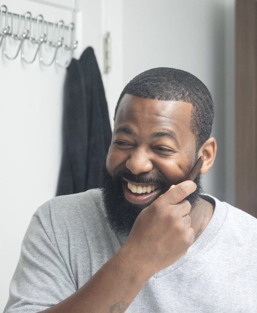 Man smiling using the best beard comb on thick dark beard