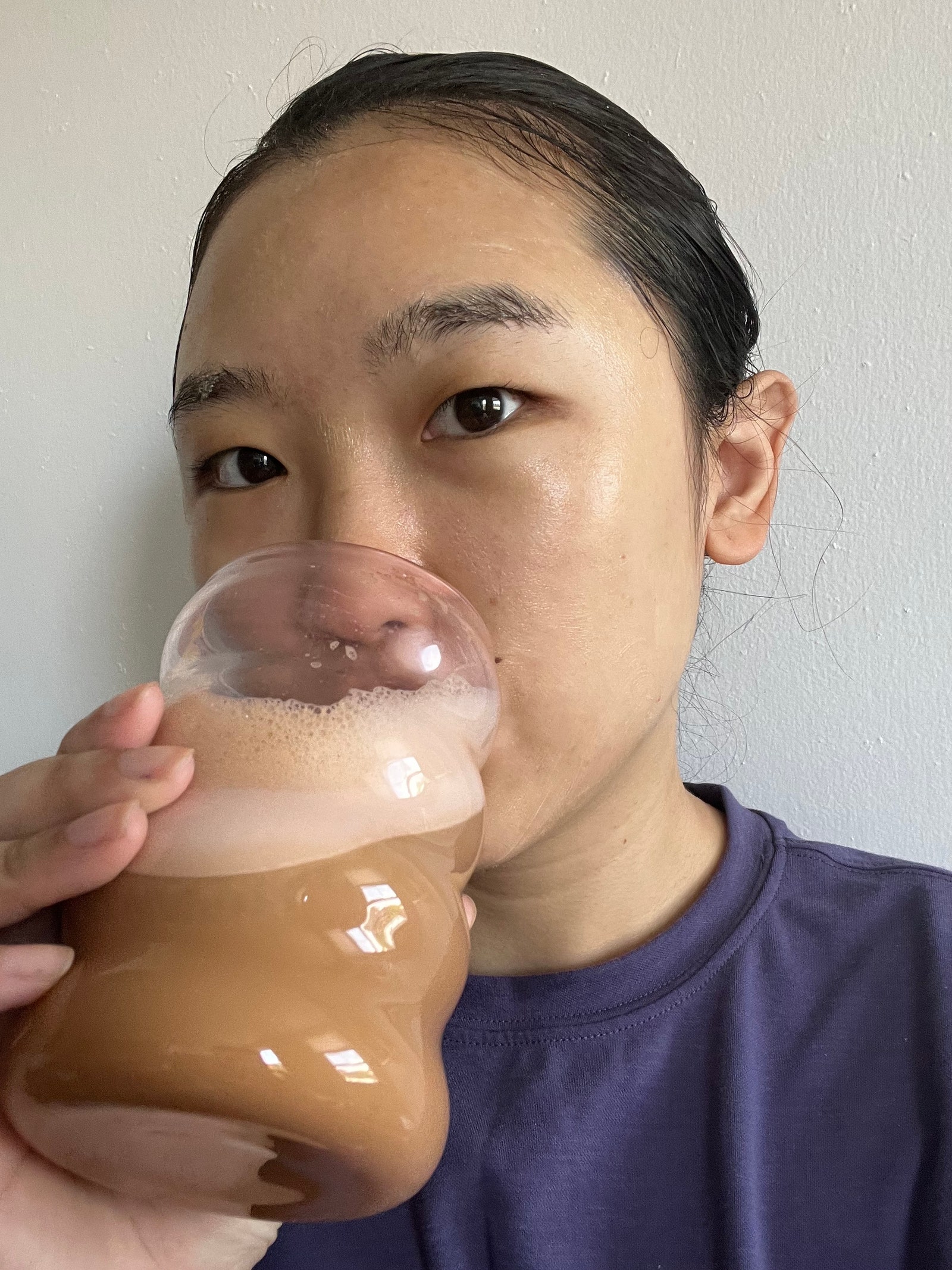 Sarah Han drinking coffee standing in front of a white wall