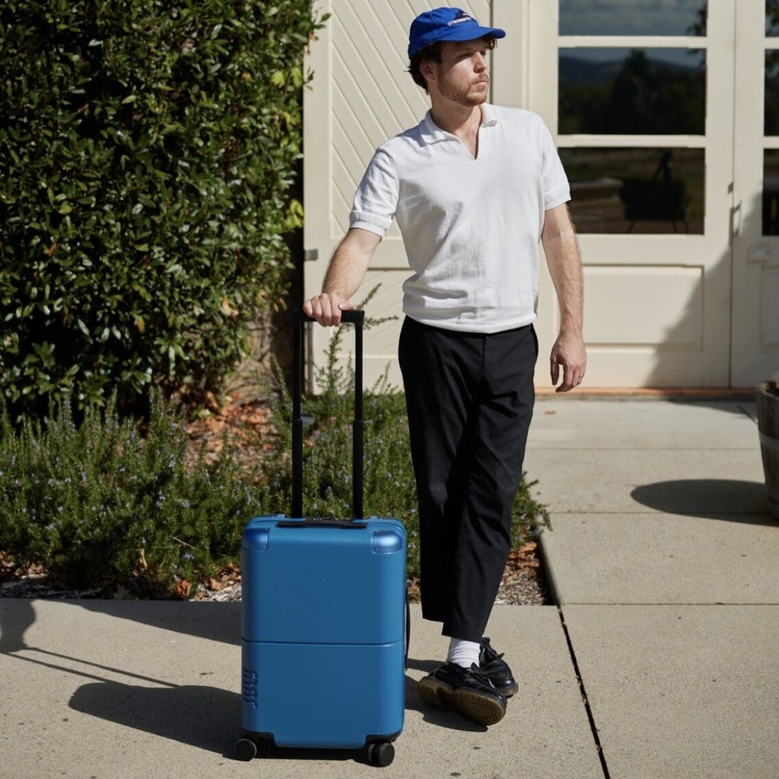 Man standing outside with a small piece of the best luggage for men