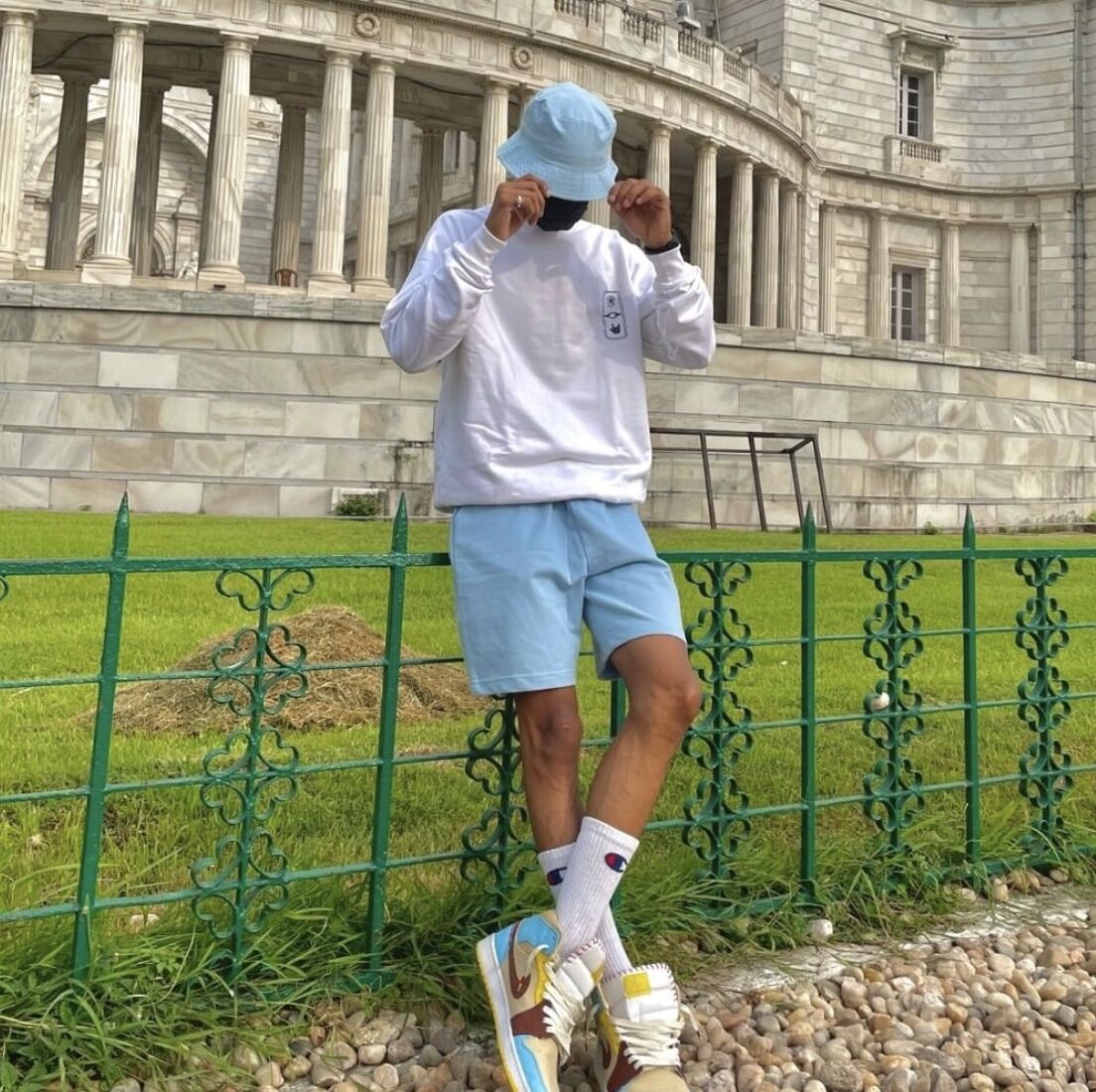 man looking down leaning against a fence wearing lounge wear