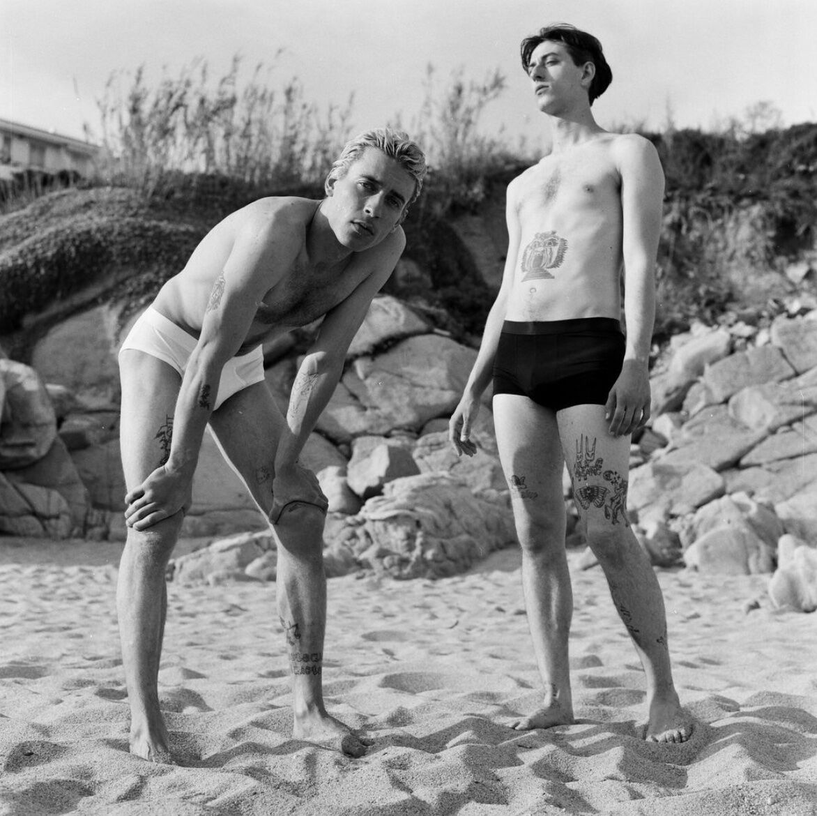 Two men with tattoos standing on the beach in the best boxer briefs