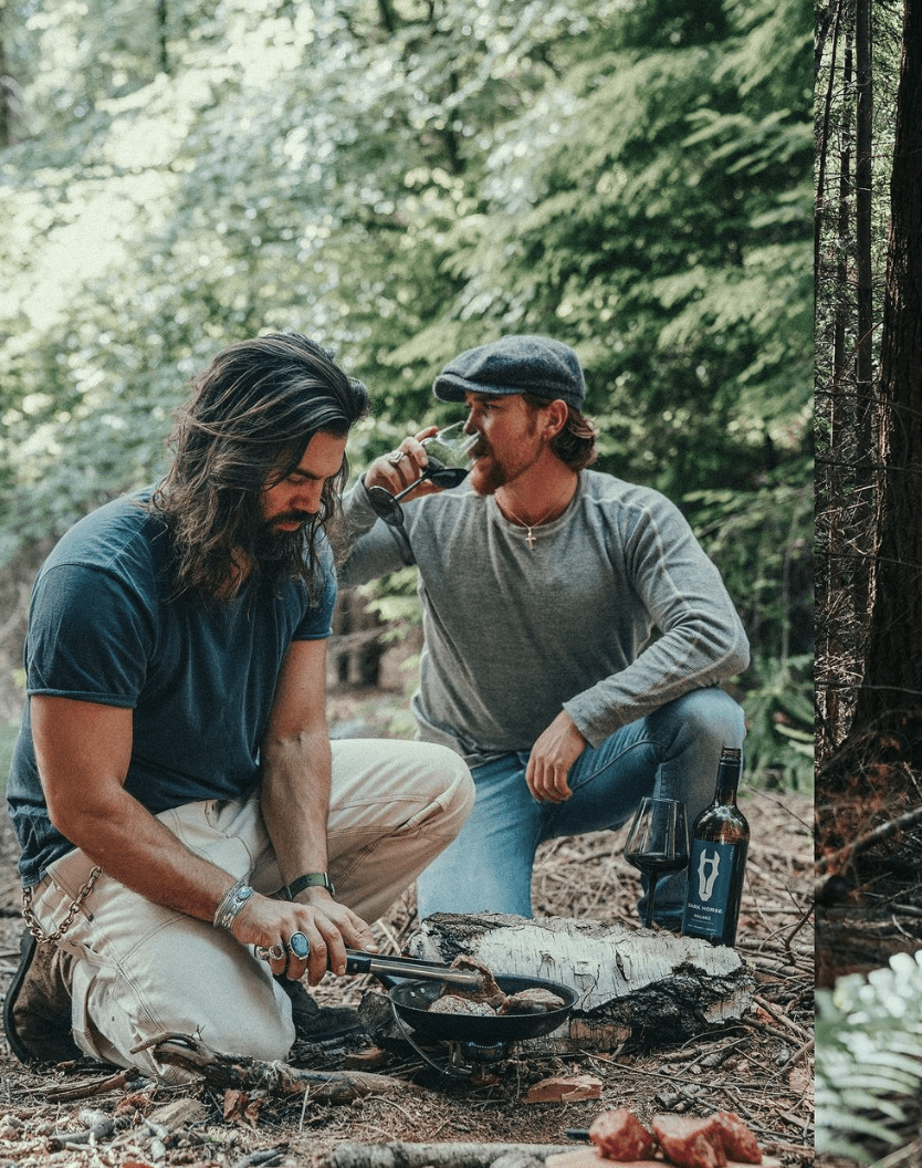 men cooking and drinking wine over a fire