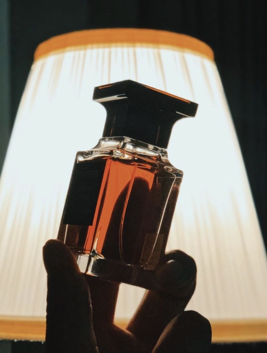 holding up cologne bottle to the light