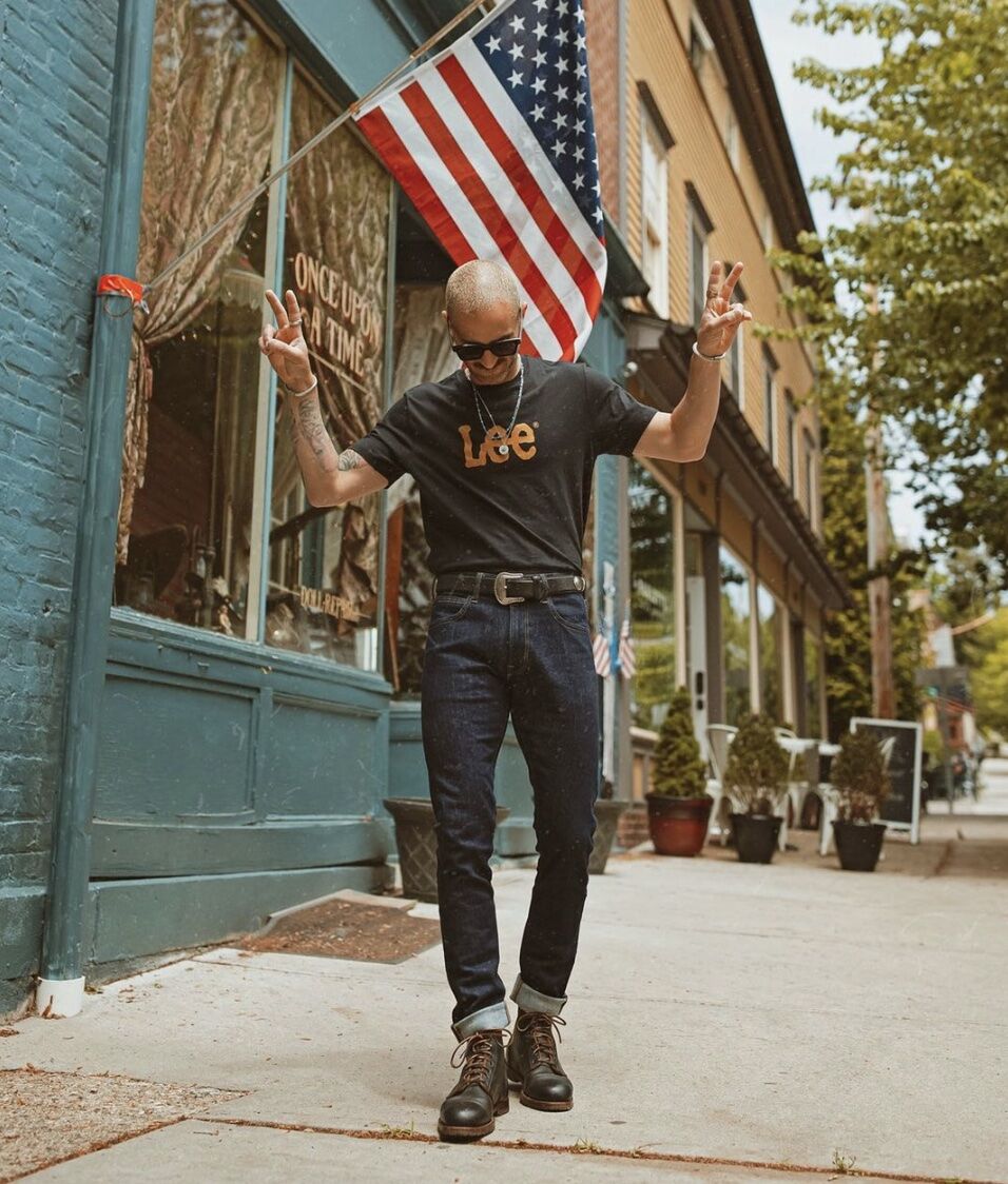 man with his hands up with peace signs wearing a western belt 