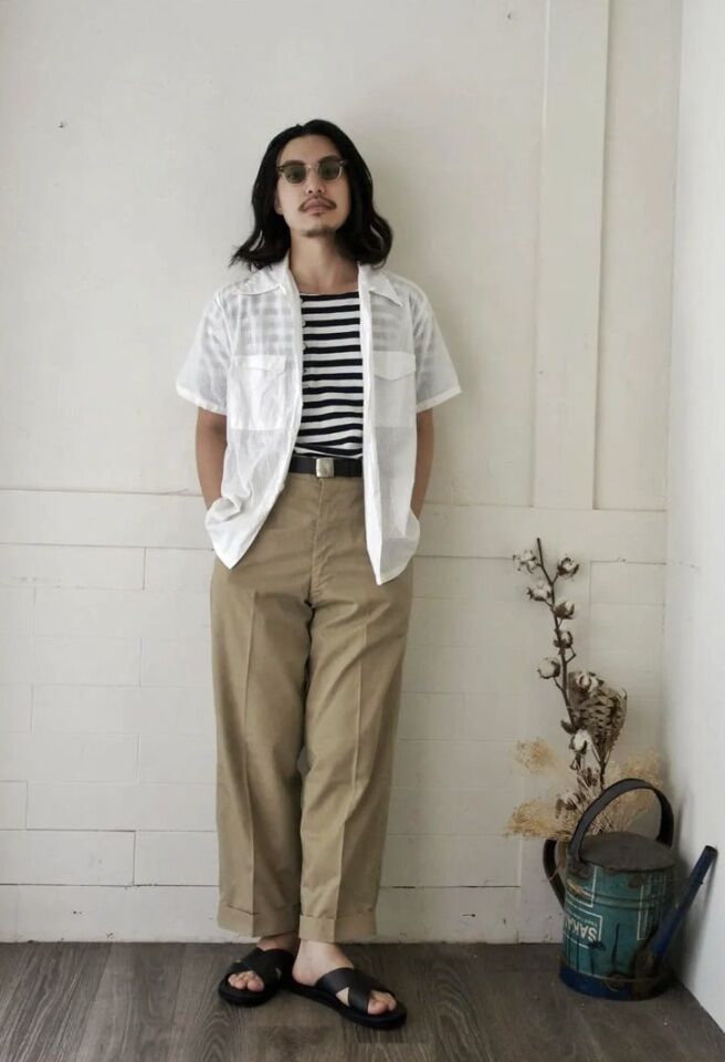 man leaning against a wall with a plant next to him