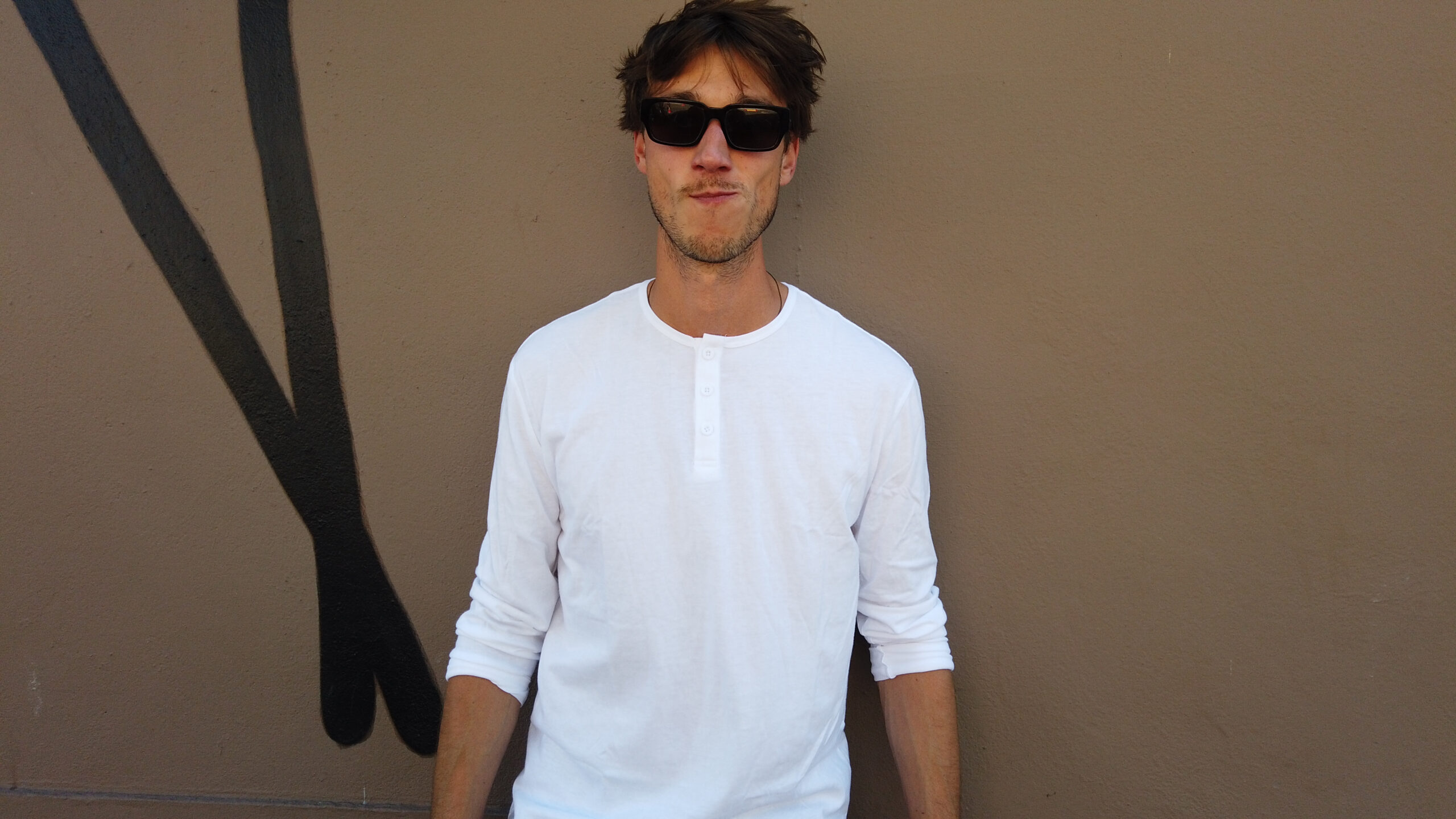 man in a white true classic tee and sunglasses smiling