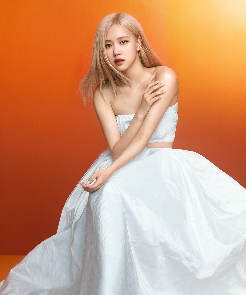 BLACKPINK's Ros posing for her Sulwhasoo campaign in front of an orange background wearing a white set